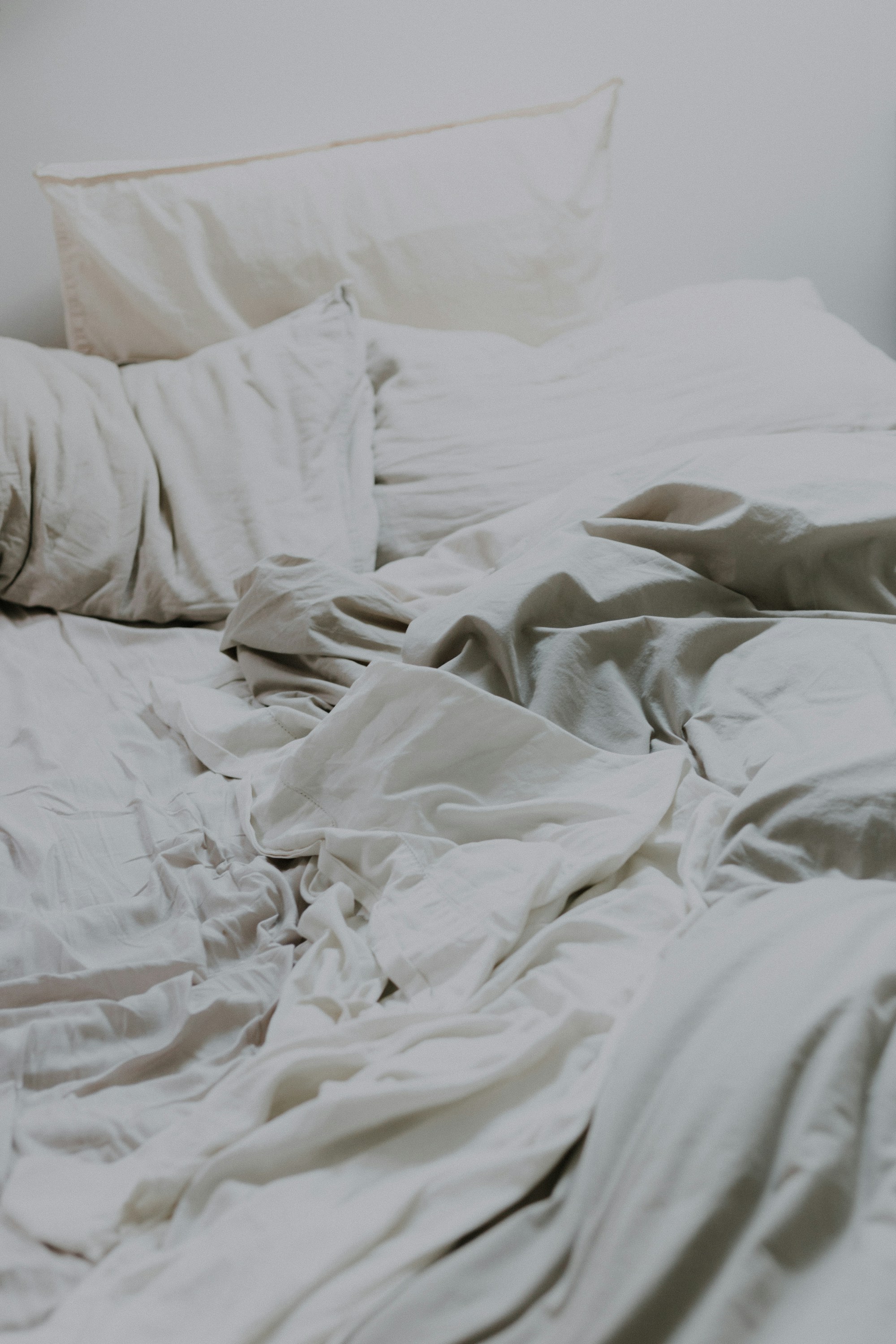 Lit défait au petit matin, draps de lin froissés et oreillers